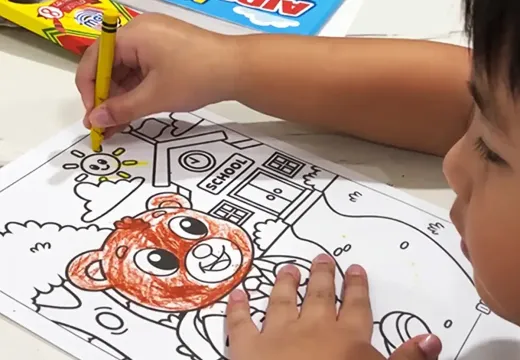 A child coloring the bear design with crayons